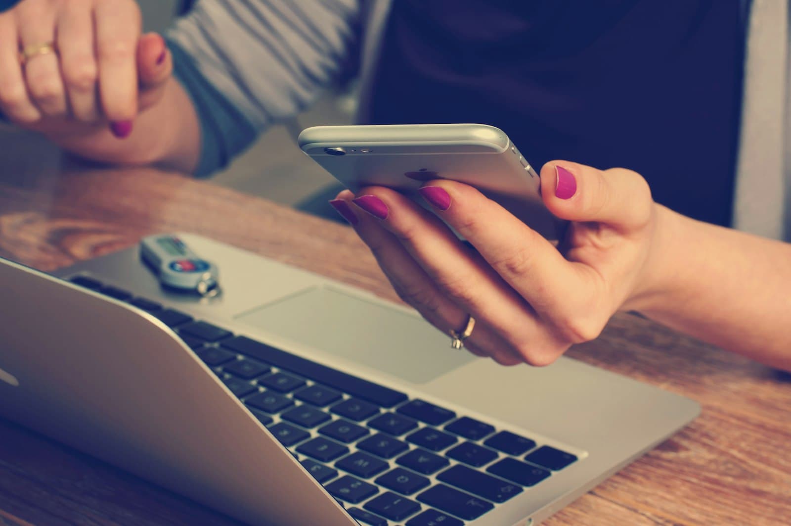 Person checking their phone next to a laptop while arranging a virtual consultation