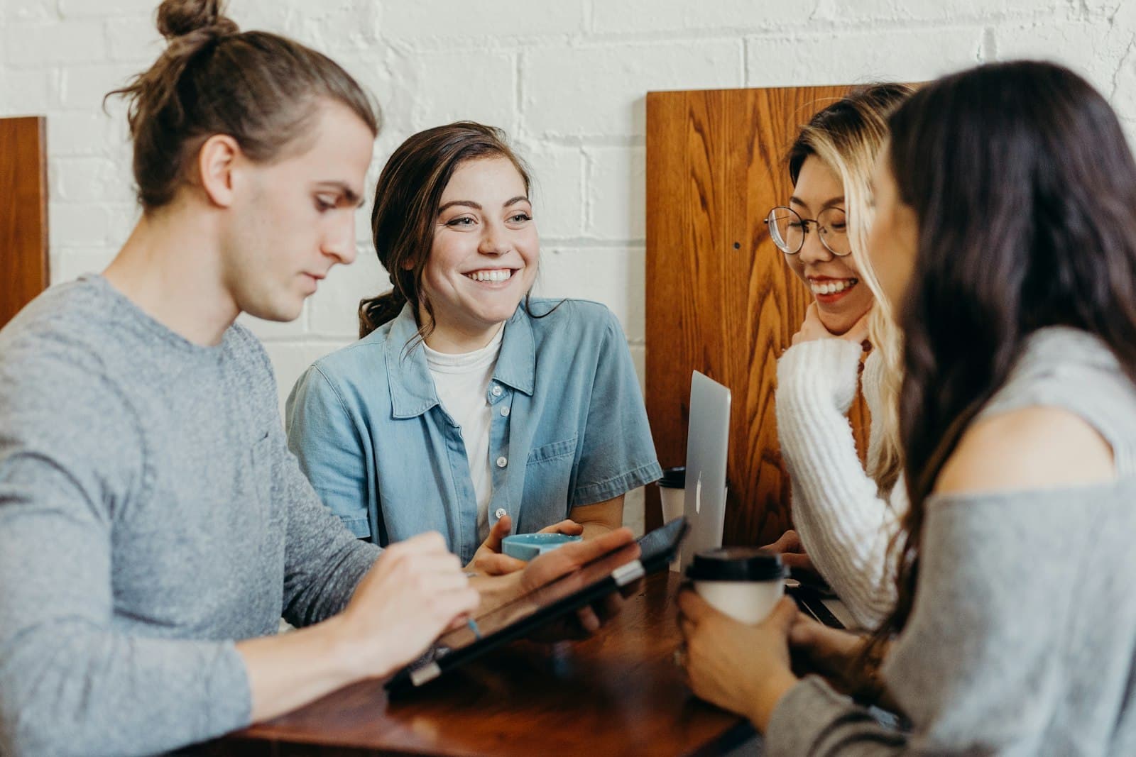 Four friends smiling and talking together around a table